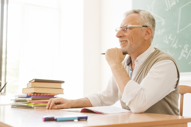 elderly lecturer sitting desk auditorium