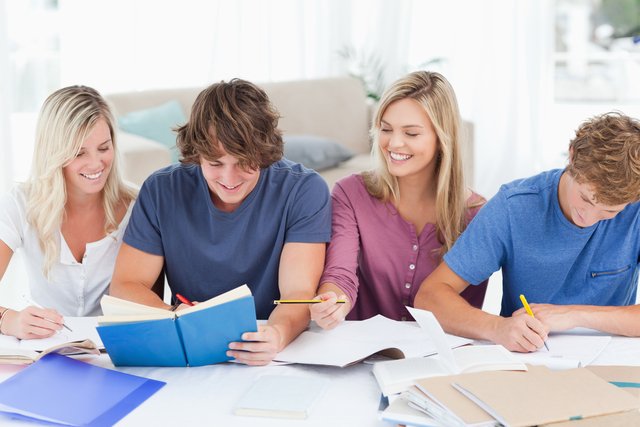 Four smiling students sitting together as they laugh while studying