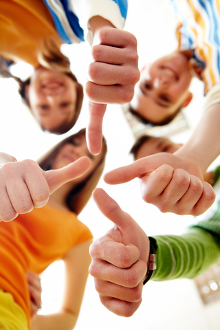 Below angle of happy teens showing thumbs up