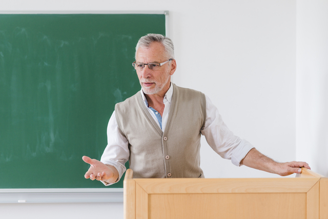 senior male professor explaining lesson near chalkboard